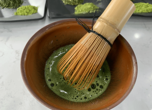 matcha tea preparation using bamboo whisk showing foam and texture